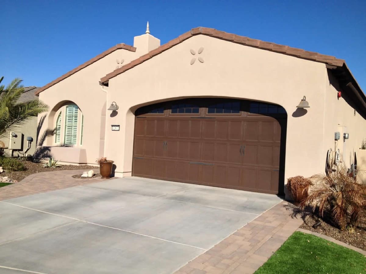 Brown custom garage door set into a beige stucco house