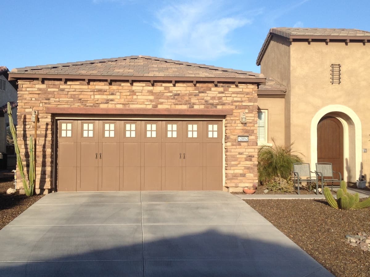 Brown garage door on a suburban house with a stone facade