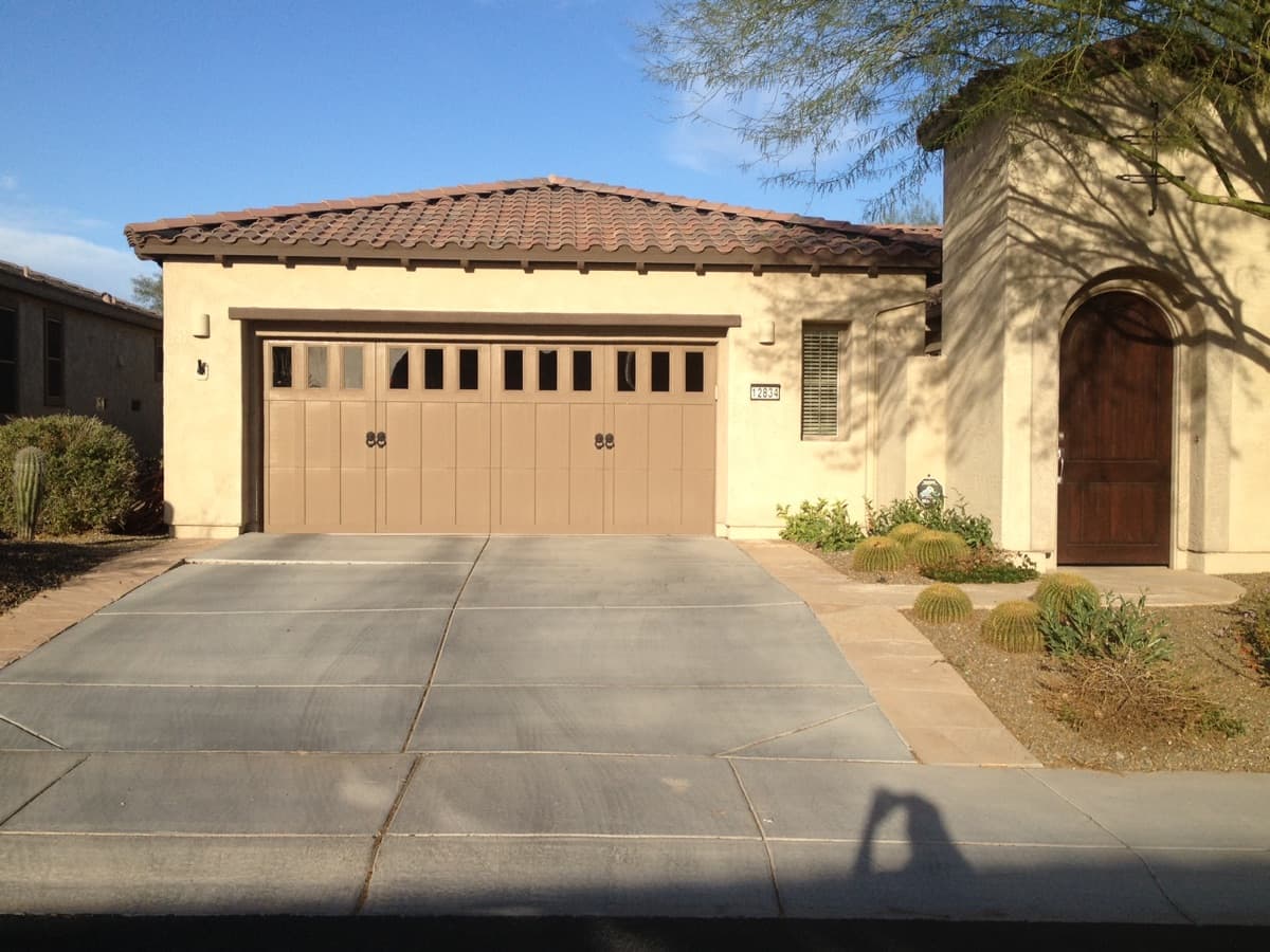 Two-car garage door on a beige stucco house with a tiled roof