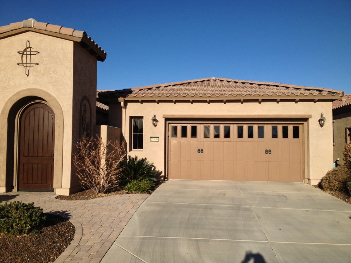 Two-car garage door on a beige stucco house under a clear blue sky