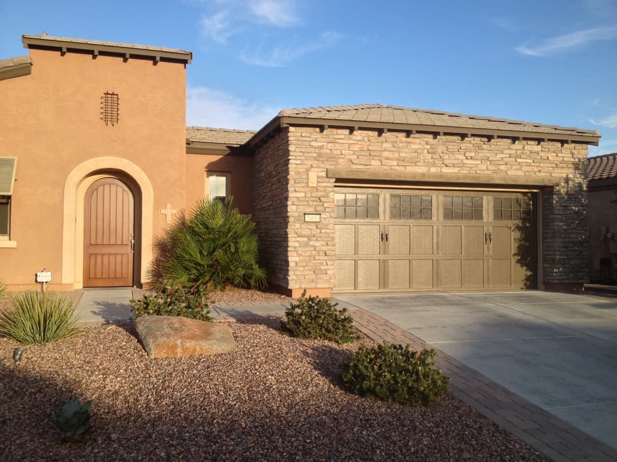 Two-car custom garage door on a modern house with stone and stucco exterior