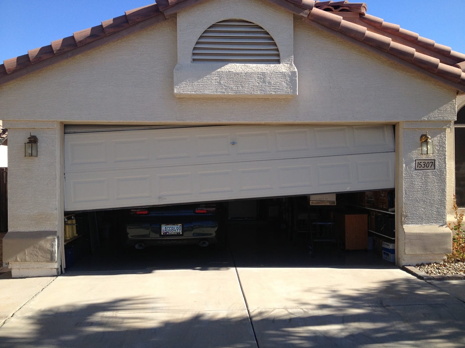 A double garage door stopped part-way open and sitting crooked in the opening