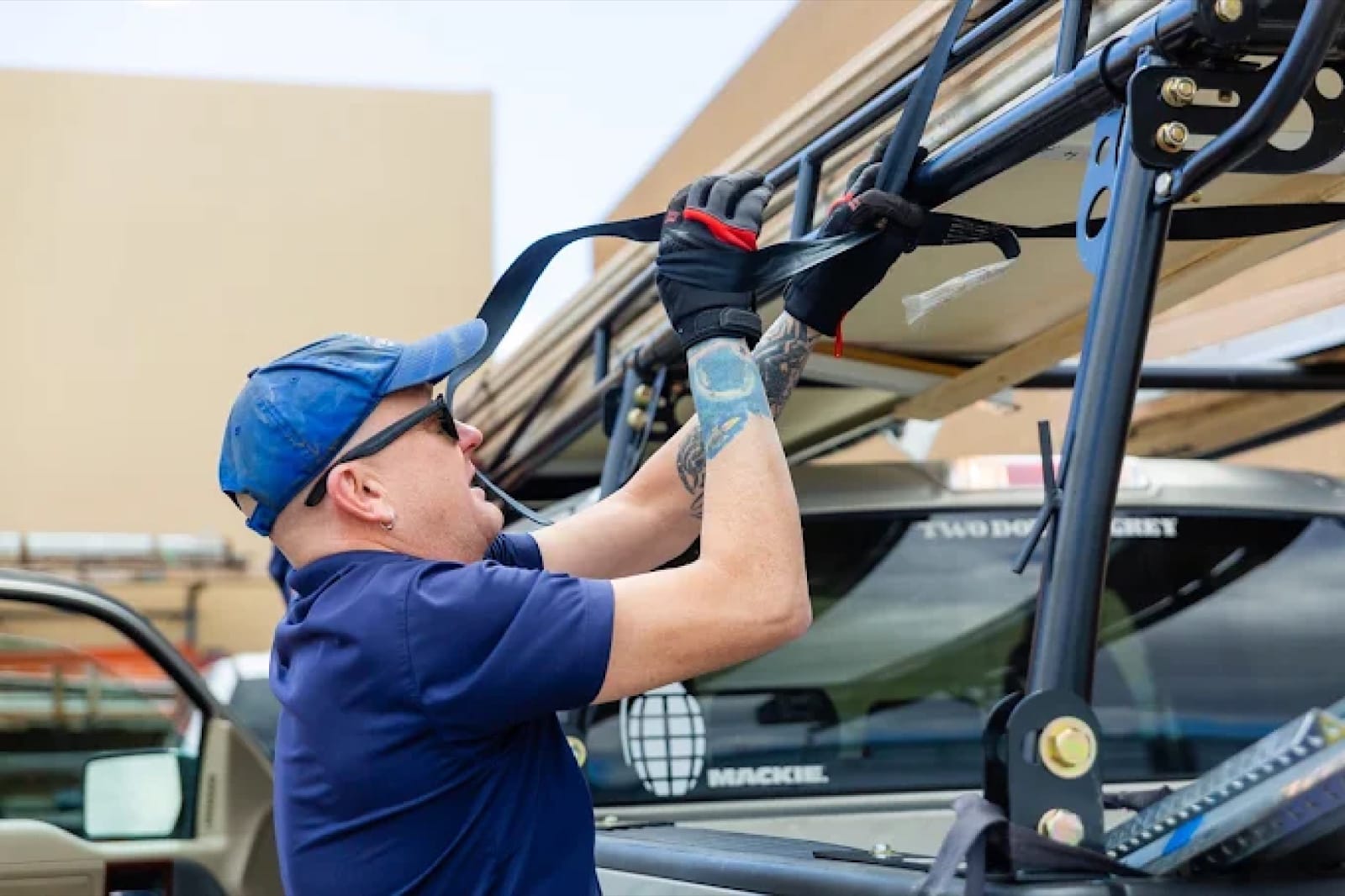A technician strapping garage door track and rail sections to the rack on a service truck